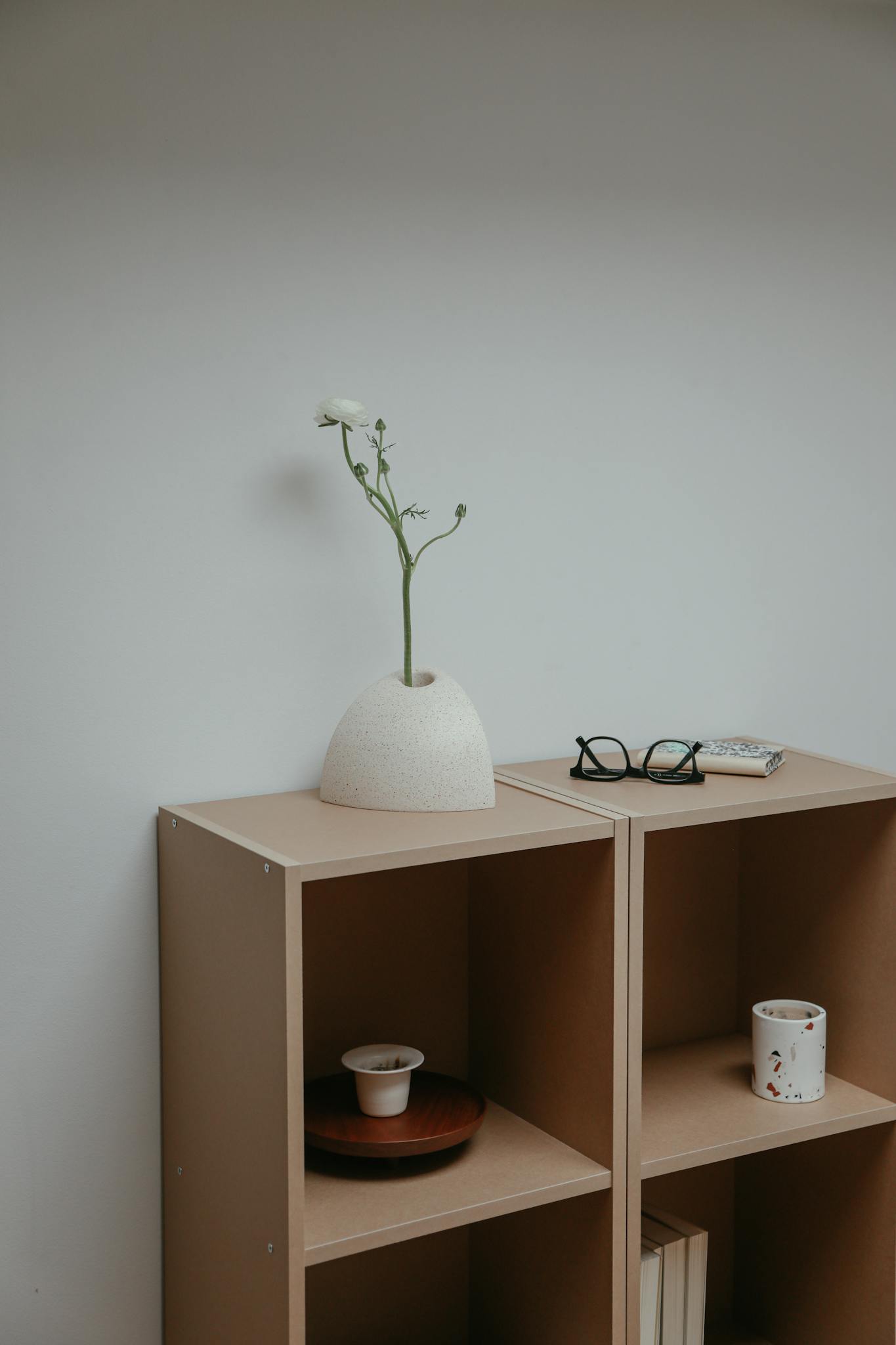 Elegant minimalist interior featuring ceramic vase on wooden shelf against a white backdrop.